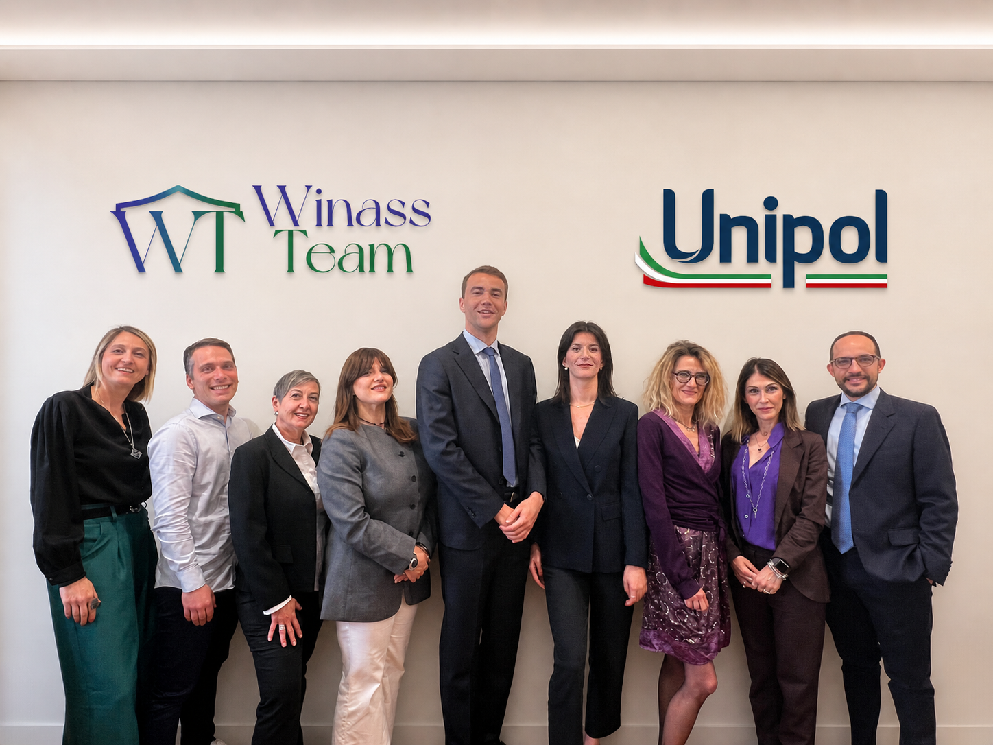 Il team Winass Team riunito in agenzia davanti al logo Unipol